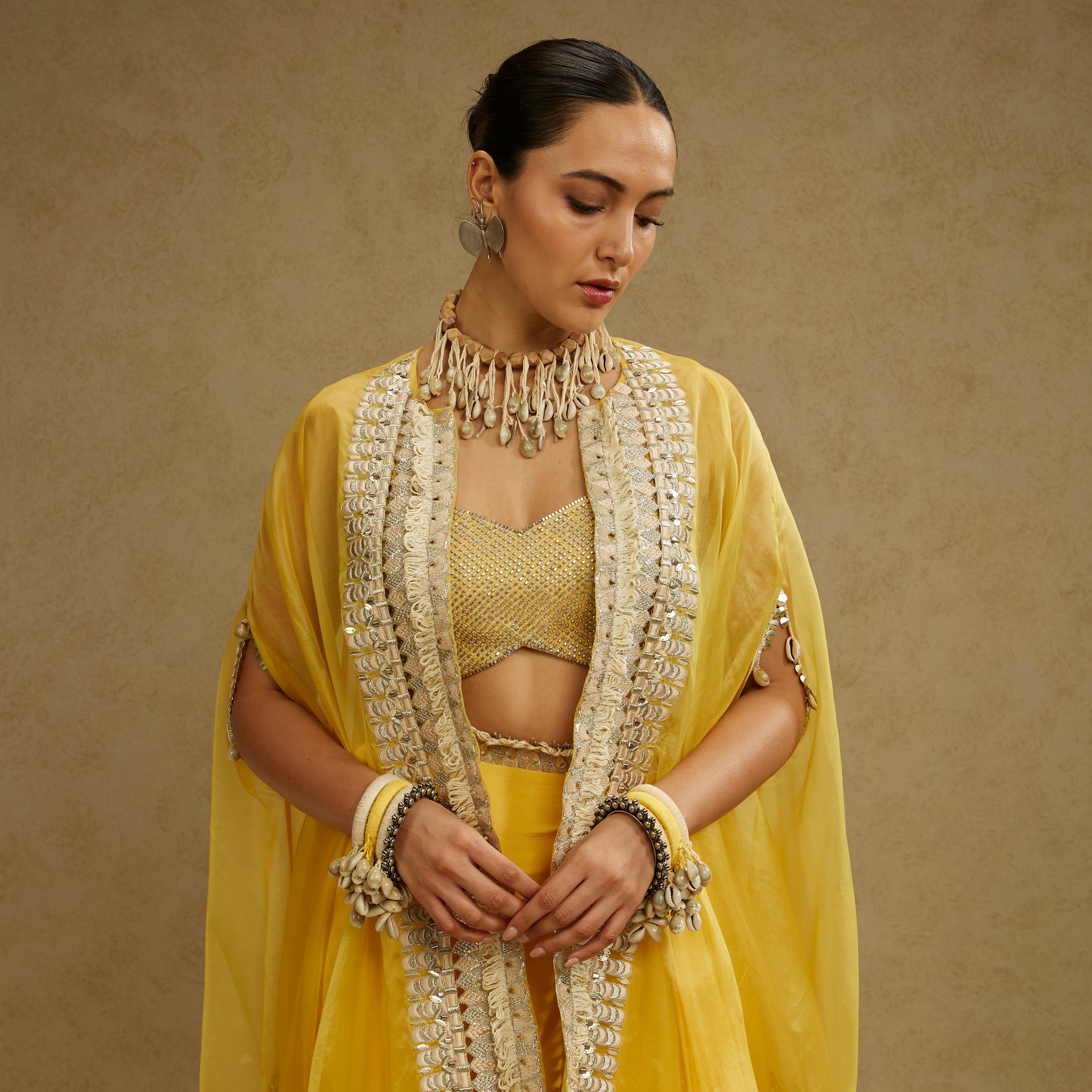 Metal Embellished Bustier Paired With Organza Cape And Yellow Drape Skirt