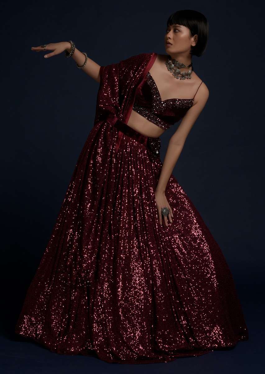 Burgundy Lehenga Embellished In Sequins With A Velvet Crop Top And Matching Belt Bag